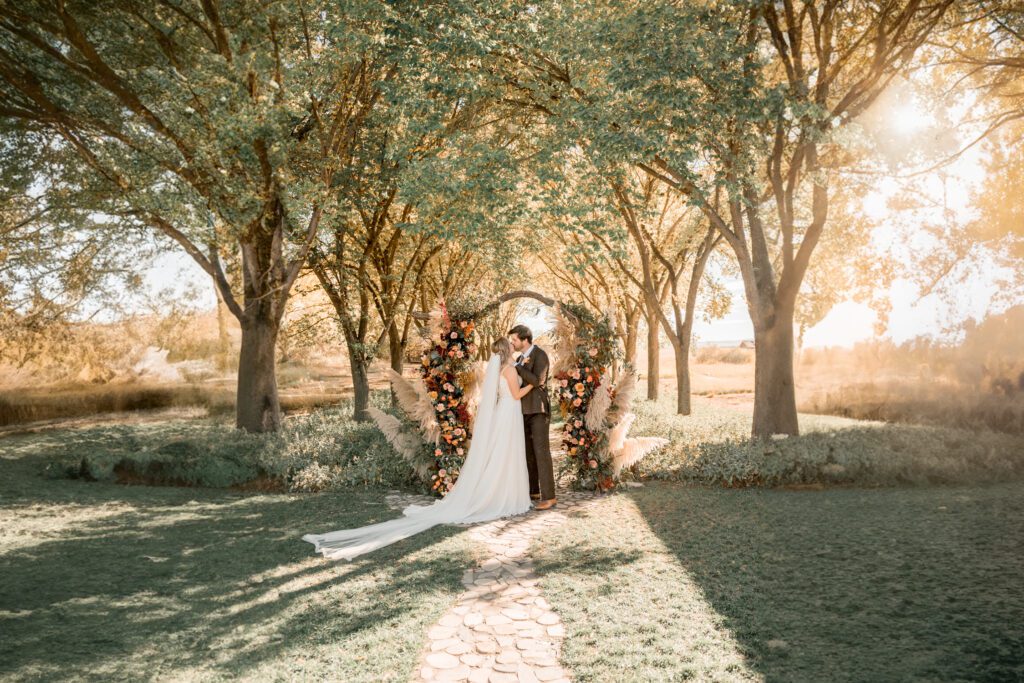 bride and groom at the coutts centre in alberta kissing at the boho archway altar for their intimate wedding